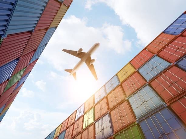 Cargo plane flying low over stacked sea containers