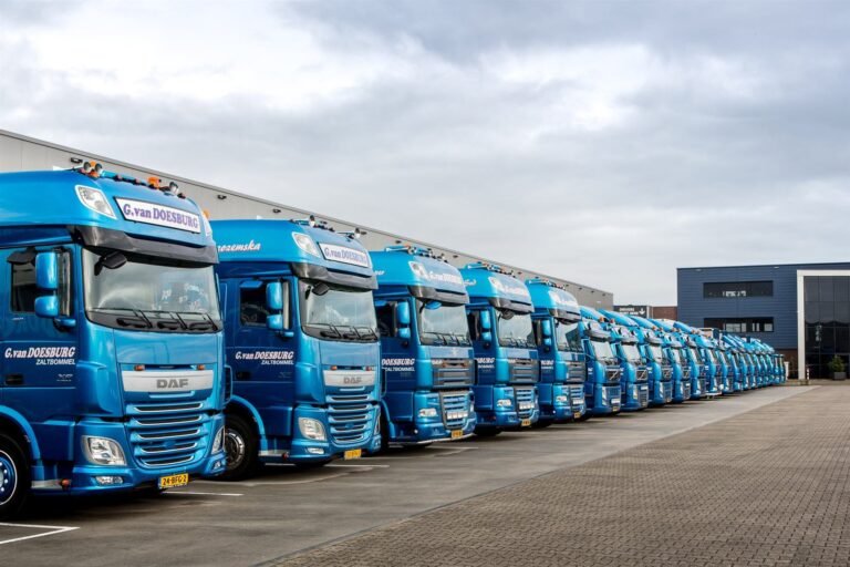 A long row of blue GD-iTS trucks parked side by side on site